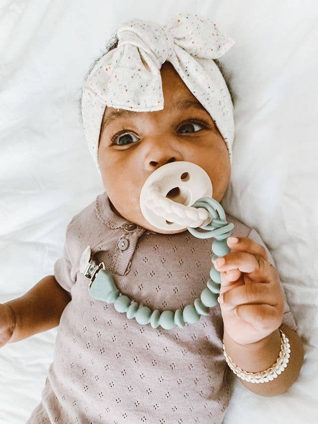 Baby with Sweetie Strap™ Silicone Pacifier Clip, stylish and secure, showcasing braided and beaded design.