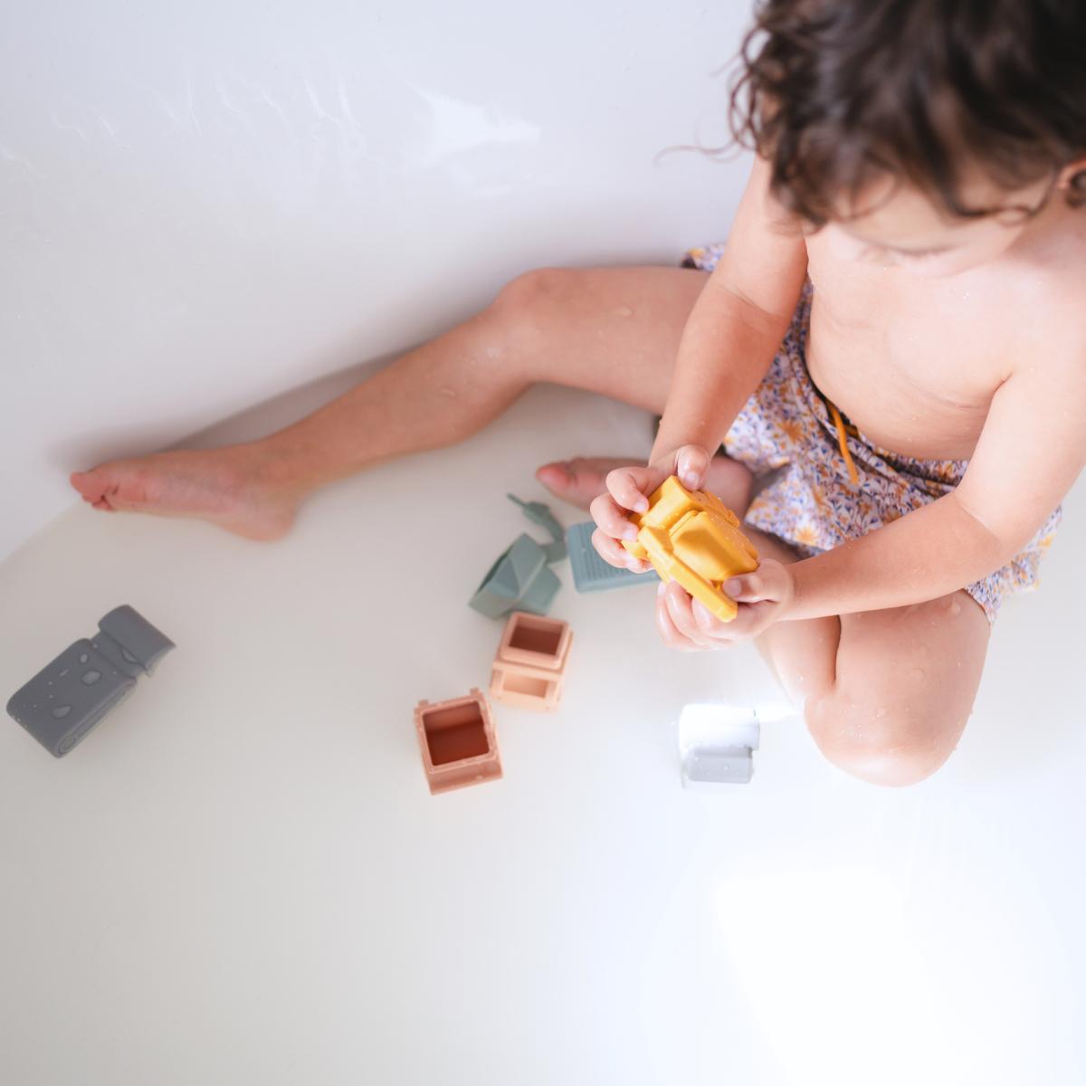 Child playing with Bug + Bean Kids Vehicle Silicone Bath Toy Set in a bathtub, featuring eco-friendly construction vehicles.