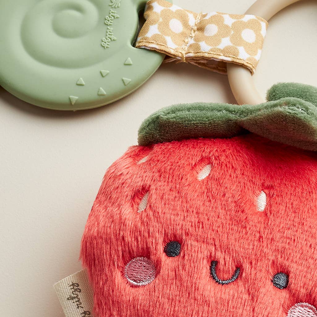 Close-up of Itzy Ritzy Strawberry Itzy Pal Plush with attached silicone teether, designed for eco-friendly teething relief and snuggles.