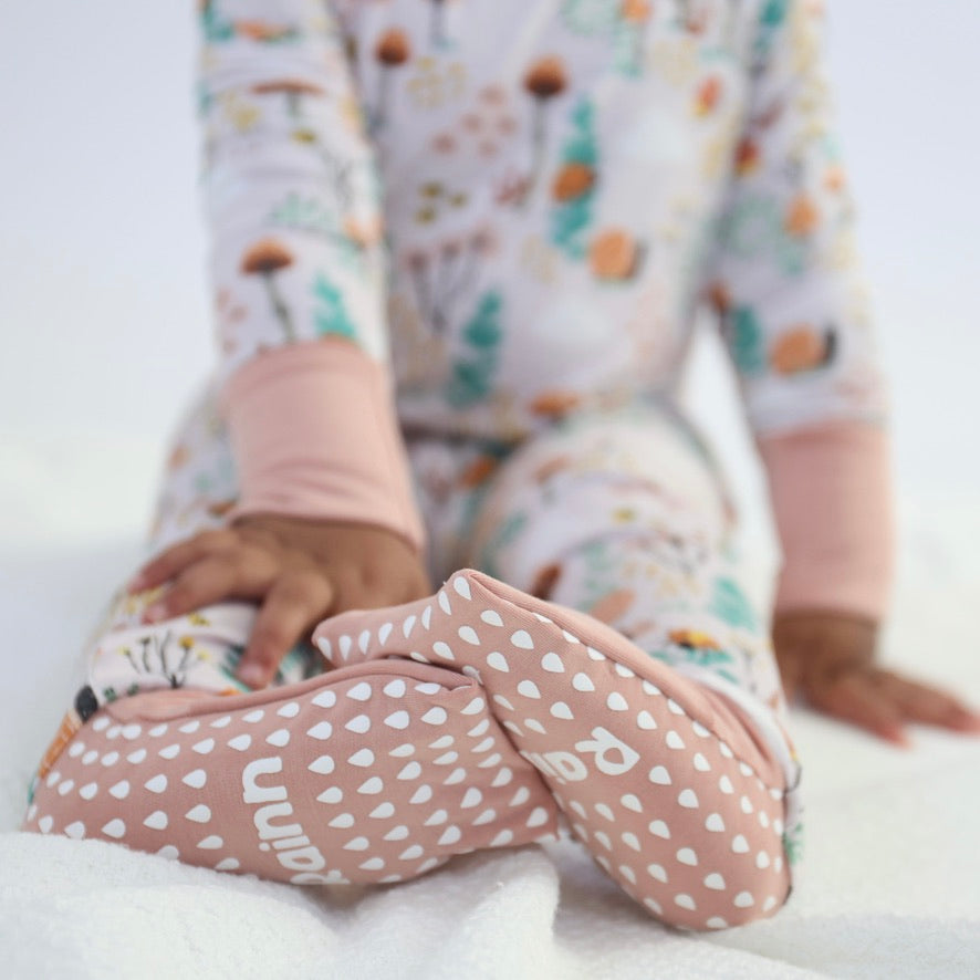 A close-up of a child's feet wearing soft pink Crescent Zipp Jammies by Rainn with playful patterns.