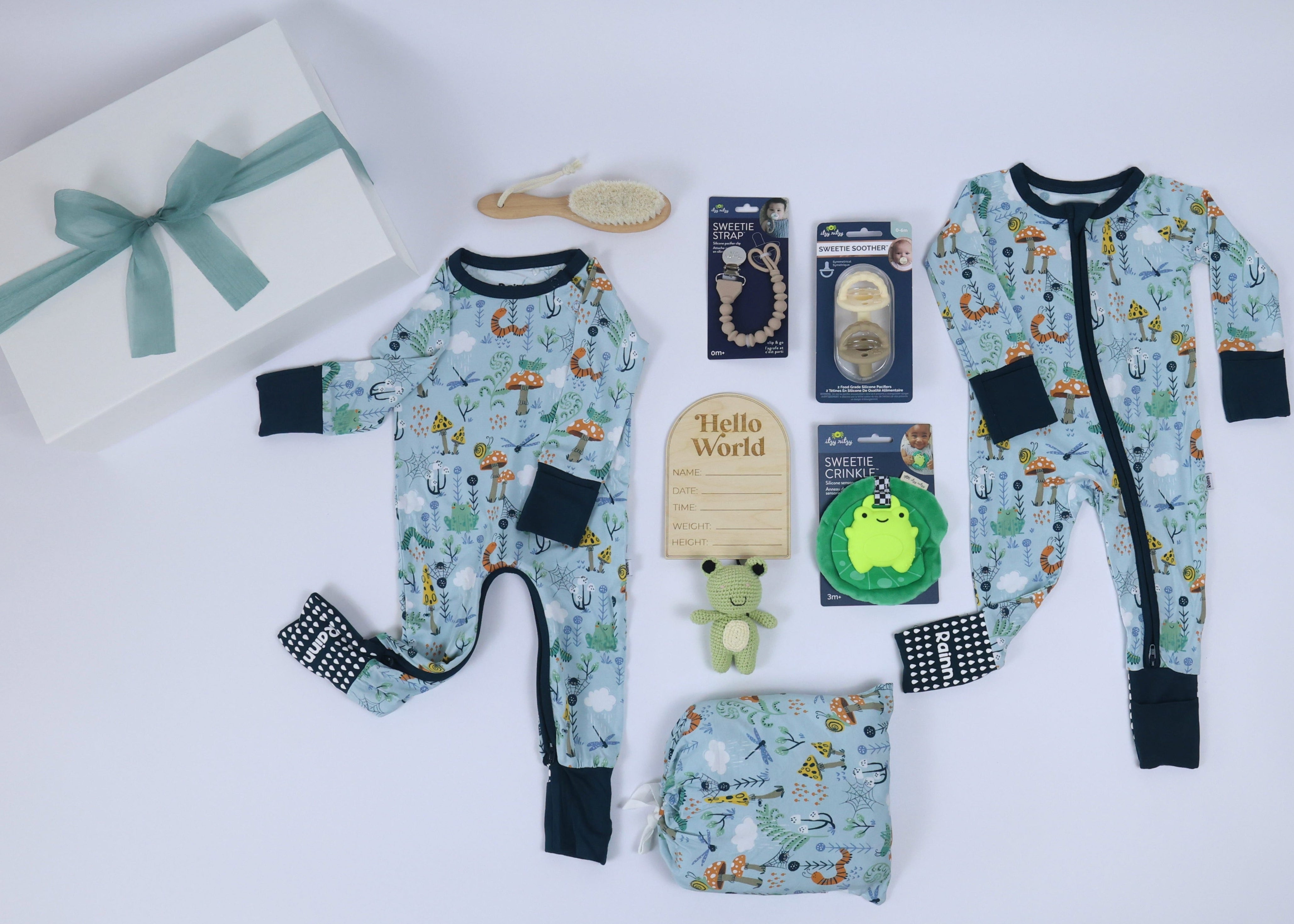 Newborn gift set featuring pajamas, pacifiers, a baby brush, and a wooden milestone card.