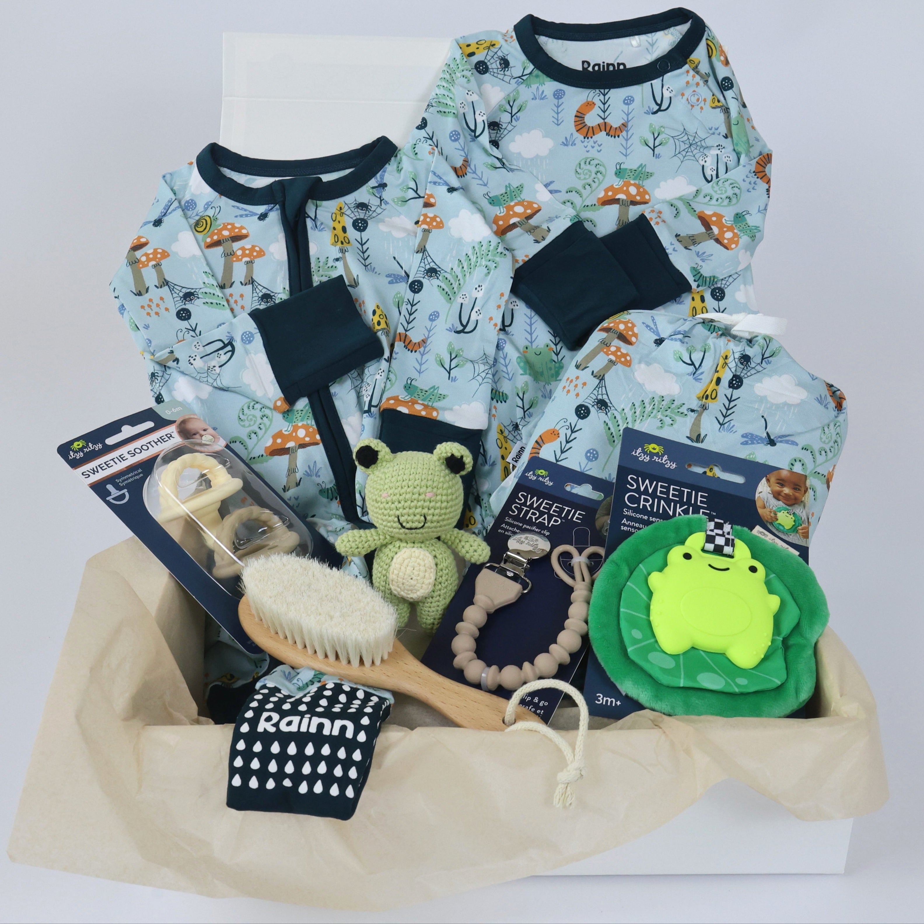 Newborn gift set featuring pajamas, pacifiers, hair brush, and toys in a gift basket for boys' nighttime.
