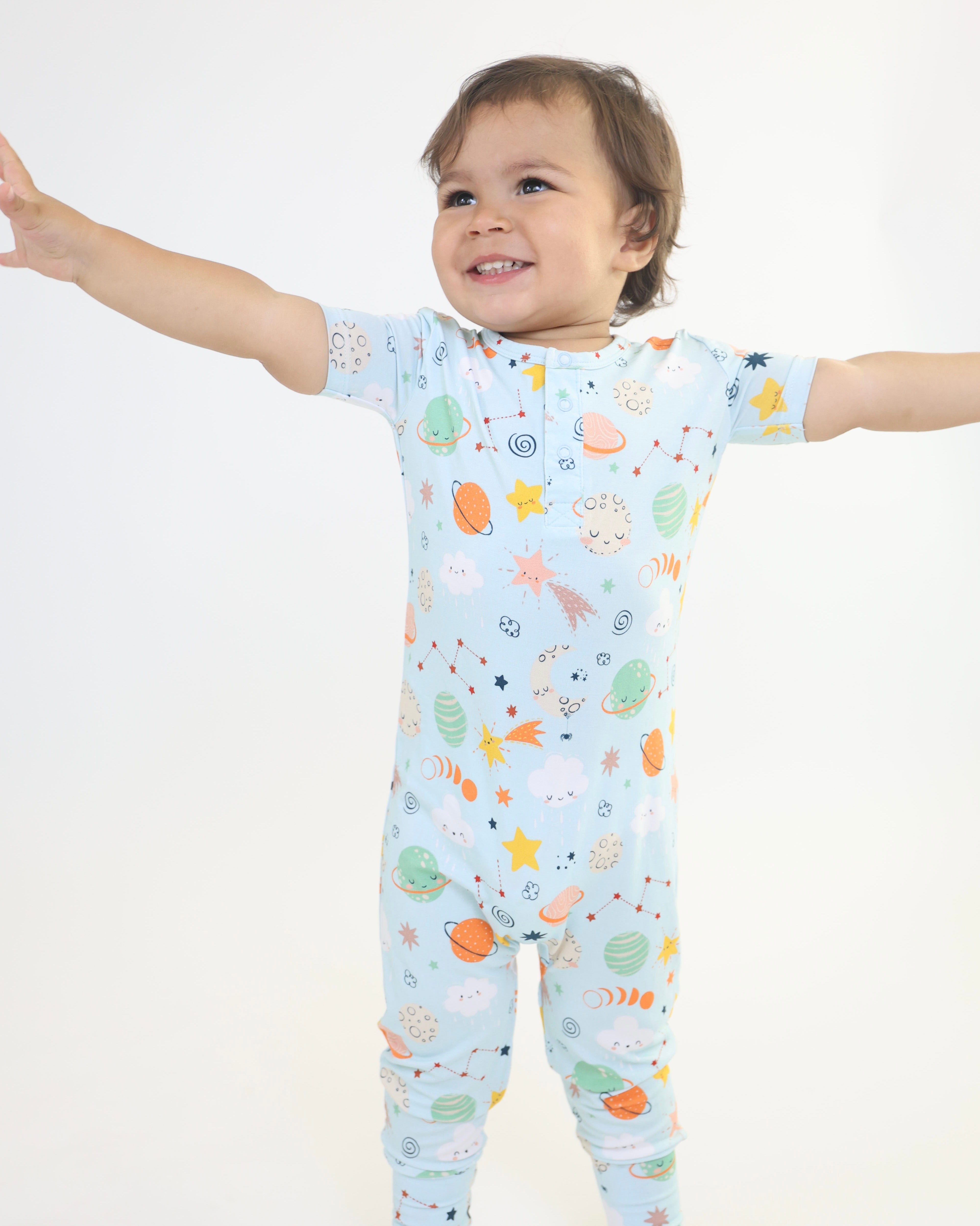 Adorable toddler in a cosmic print pull-up romper, showcasing soft bamboo stretch and playful designs.